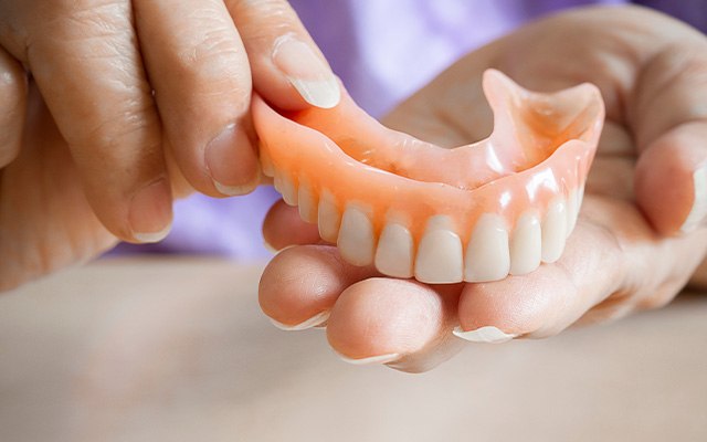 A patient holding an upper denture