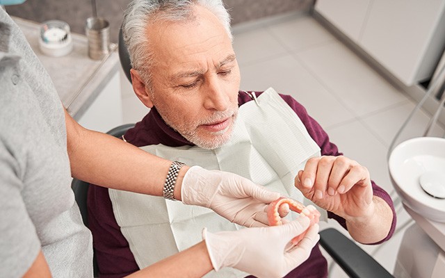 Dentist showing male patient full dentures