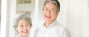 Middle-aged couple smiling while wearing dentures in Chaska