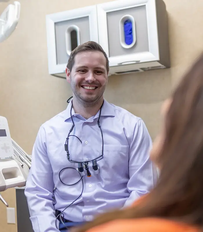 Woman with glasses talking to her dentist while in the dental chair