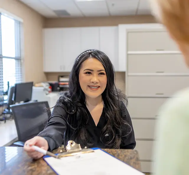 Dental team member showing forms to a patient at desk