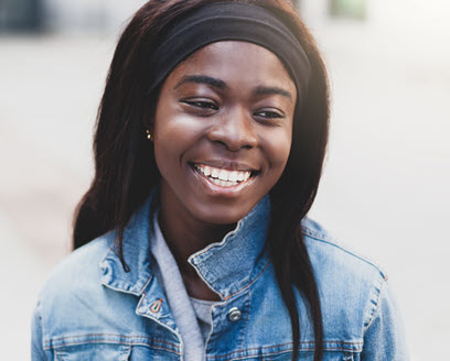 Person in denim jacket smiling outside